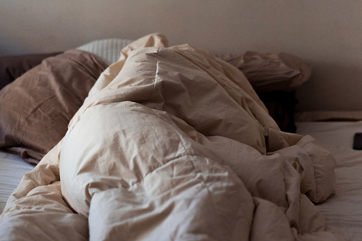 Person im Bett unter Bettdecke