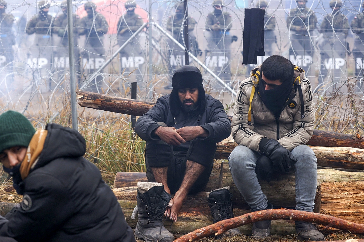 Migranten nahe Grodno, im Hintergrund polnische Grenzschütze