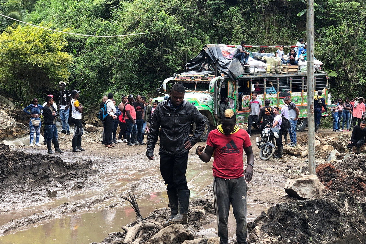 Buspassagiere bahnen sich nach einem Erdrutsch ihren Weg durch den Schlamm