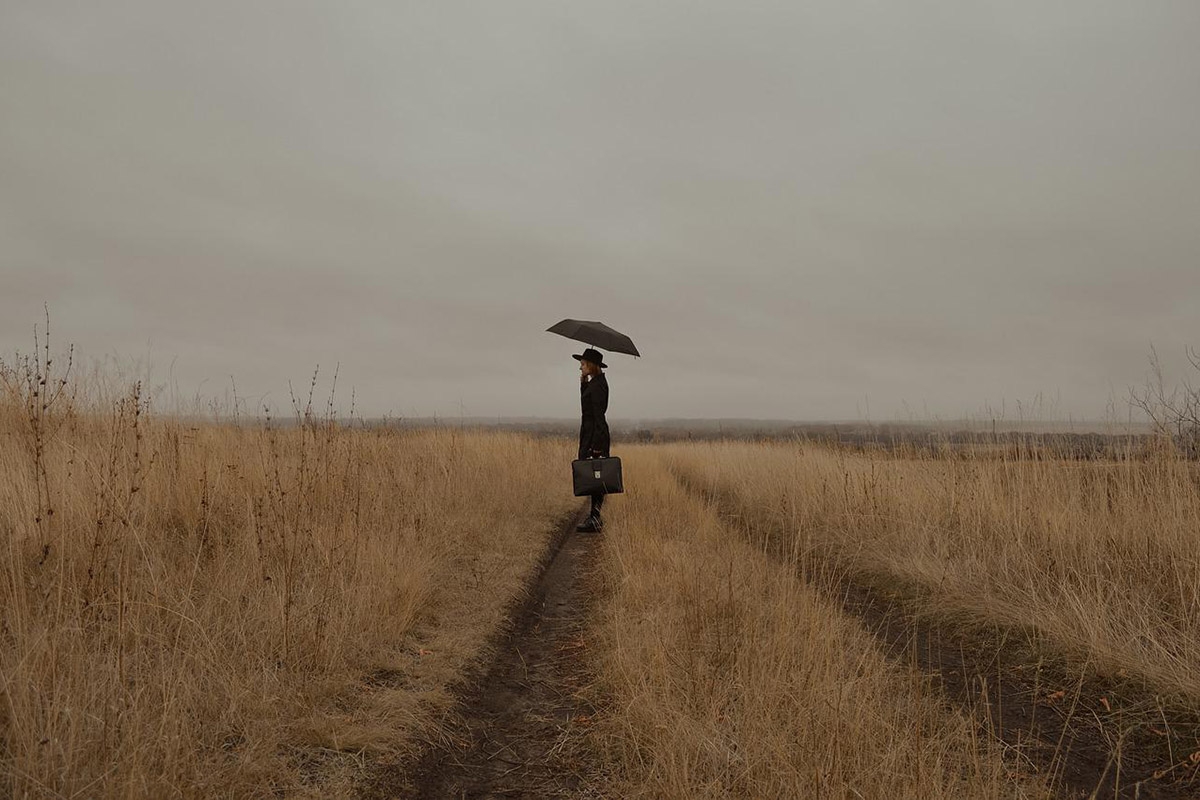 Frau mit Regenschirm steht auf einem Feld
