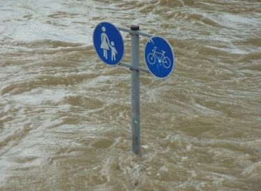 Schild mit Zeichen für Fußgänger und Fahrradfahrer ragt aus Hochwasser