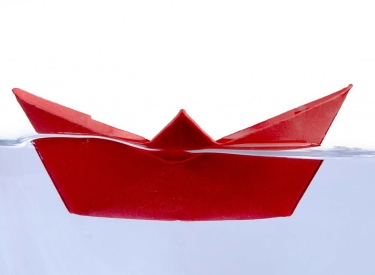 Rotes Papierschiff im Wasser