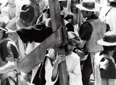 Filmbild in Schwarzweiß: Jesus trägt ein Kreuz