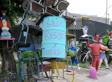 eine Skulptur aus Stühlen und einem Ölfass mit der Aufschrift "Siloe resiste - y usted?"