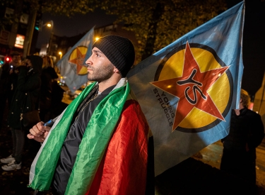 Ein Mann mit Fahne von Young Struggle und einer Palästinenser-Fahne auf den Schultern, bei einer Kundgebung in Duisburg am 12. Oktober