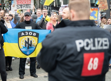 Ein Mann zeigt während einer Demonstration in Frankfurt im September 2022 eine Flagge in den Farben der Ukraine mit dem Wappen des Asow-Bataillons in der Version bis 2015, mit »Schwarzer Sonne« und Wolfsangel